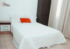 a white bed with a red pillow on top of it at Casa 65 San Miguel in San Miguel