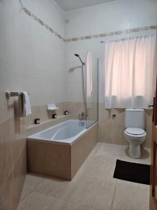 a bathroom with a bath tub and a toilet at Ruby Heaven Apartment in St Paul's Bay