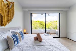 a bedroom with a large bed with a large window at Menesse Apartments in Tulum +57 photos