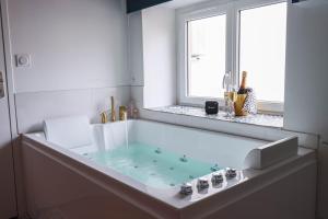 a white bathroom with a tub with a window at Suite Saphir - Jacuzzi & Sauna in Saint-Étienne