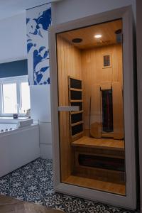 een badkamer met een douche en een houten muur bij Suite Saphir - Jacuzzi & Sauna in Saint-Étienne