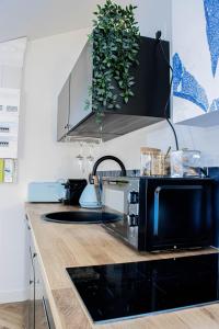 a kitchen with a counter with a black microwave at Suite Saphir - Jacuzzi & Sauna in Saint-Étienne +25 photos