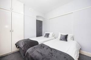 two beds in a room with white walls and white cabinets at 1 Bedroom Flat in Bromley in Hither Green