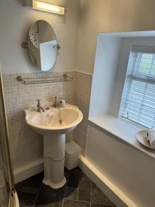 ein Bad mit einem Waschbecken und einem Spiegel in der Unterkunft Superbly appointed 300 year old stone cottage in Bakewell