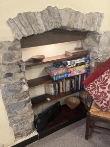 einen Steinkamin mit einem Bücherregal voller Bücher in der Unterkunft Superbly appointed 300 year old stone cottage in Bakewell