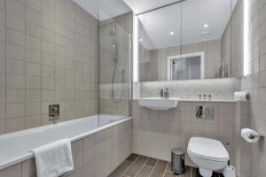 La salle de bains est pourvue de toilettes, d'un lavabo et d'une baignoire. dans l'établissement Spacious Two Bedroom Apartment at Wembley Park, à Londres