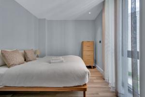 ein Schlafzimmer mit einem weißen Bett und einem großen Fenster in der Unterkunft Spacious Two Bedroom Apartment at Wembley Park in London