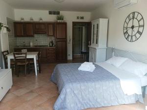 a bedroom with a bed and a kitchen with a clock on the wall at La casina delle Sorgentelle in Bagni San Filippo