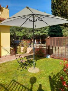 a table and chairs under an umbrella in the grass at La casina delle Sorgentelle in Bagni San Filippo
