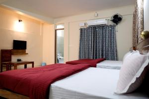 a bedroom with two beds with red sheets and a window at HILL PALACE RESIDENCY COORG in Virajpet