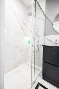 een witte badkamer met een douche en een wastafel bij VipWarsawApartments Sapphire Mennica Residence in Warschau
