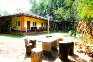 a yellow house with a table in front of it at Isiri river side stay in Kalasa