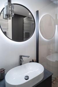 a bathroom with a white sink and a mirror at Apartament White Glove Deluxe Stara Warszawska in Olsztyn