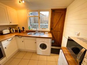 a kitchen with a washing machine and a sink at Crown Cottage - Charming 2 Bed Cottage in Dudbridge