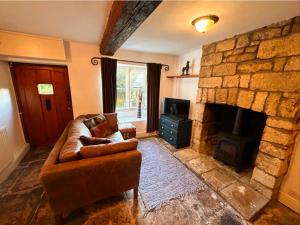 salon z kanapą i kamiennym kominkiem w obiekcie Crown Cottage - Charming 2 Bed Cottage w mieście Dudbridge