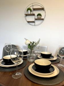 a wooden table with plates and wine glasses on it at Spacious One Bedroom Apartment in Hemel Hempstead