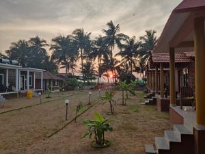 a village with palm trees and a sunset in the background at Niyam Beach Stay in Gokarna