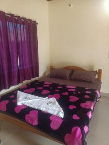 ein Schlafzimmer mit einem Bett mit einer lila Tagesdecke in der Unterkunft Niyam Beach Stay in Gokarna