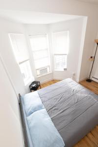 ユニオンシティにあるMins to NYC Captivating warm studio aptの白いベッドルーム(ベッド1台、窓3つ付)