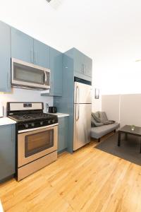 ユニオンシティにあるMins to NYC Captivating warm studio aptのキッチン(青いキャビネット、コンロ、冷蔵庫付)