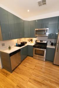 a kitchen with gray cabinets and stainless steel appliances at Mins to NYC Captivating warm studio apt in Union City