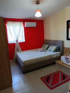 - une chambre avec 2 lits et un mur rouge dans l'établissement Dina's House, à Leondari