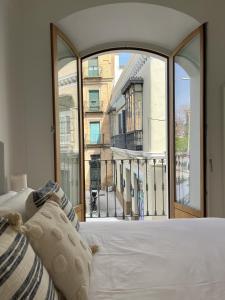 Bett in einem Zimmer mit einem großen Fenster in der Unterkunft Balcones de Jauregui Premium Apartment in Sevilla
