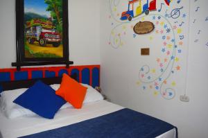 菲蘭迪亞的住宿－FILANDIA HOTEL，一间卧室配有一张带色彩缤纷枕头的床和一幅画