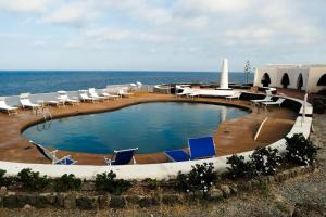 una piscina con tumbonas y el océano en Pantelleria, villetta sul mare, en Scauri