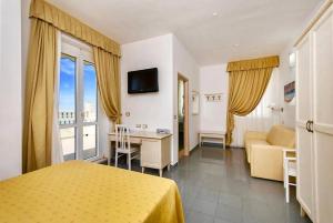 a hotel room with a bed and a couch and a television at Hotel Marechiaro - Direttamente sul mare in Vico del Gargano