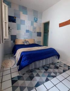 a bedroom with a bed with a blue blanket on it at Hospedaria Guapê in Lauro de Freitas