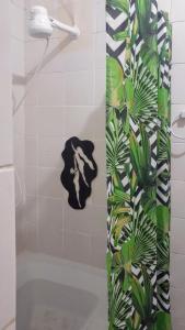 a bathroom with a shower curtain with a plant at Hospedaria Guapê in Lauro de Freitas