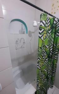 uma casa de banho com um chuveiro com uma cortina de chuveiro com plantas em Hospedaria Guapê em Lauro de Freitas