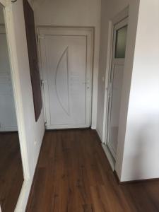 un couloir vide avec une porte blanche et du parquet. dans l'établissement Stan - Mostar, à Mostar