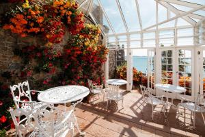 a patio with tables and chairs and flowers in a greenhouse at Panorama Guest House in Saint Aubin