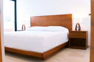 een slaapkamer met een groot bed met een houten hoofdeinde bij Luxury 3BR Oceanfront Retreat - Pool, Views & Private Beach Access in Chicxulub