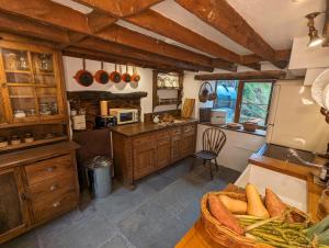 una cocina con armarios de madera y una cesta de verduras en Voulwill Cottage en Lynton
