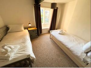 a bedroom with two beds and a window at Crown Cottage - Charming 2 Bed Cottage in Dudbridge