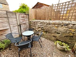 a patio with three chairs and a table and a fence at Crown Cottage - Charming 2 Bed Cottage in Dudbridge
