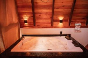 uma banheira na casa de banho com tecto em madeira em Pousada Sestrem - São João Batista - SC em São João Batista