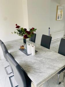 uma mesa de mármore com cadeiras e um vaso com flores em New Malden, 3 Bedroom Guest House em Malden