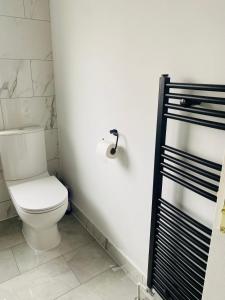 uma casa de banho com um WC e um suporte de papel higiénico em New Malden, 3 Bedroom Guest House em Malden