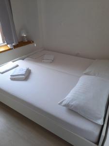 a white bed with two towels on top of it at Hostel Jadran in Pag