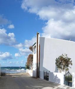 a white building on the beach with the ocean in the background at Salty Beach Cottage, 20m from Kini Beach in Ano Syros