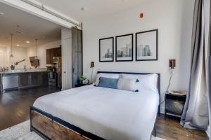 a bedroom with a large white bed and a kitchen at Lofts at 30th - 2 Top Floor Units in Nashville