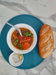 a plate with a bowl of soup and a loaf of bread at Myrtle Boutique Hotel Phu Quoc in Phu Quoc