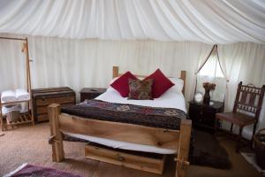 a bedroom with a bed with red pillows and a canopy at Elessar Yurt Village in Chichester