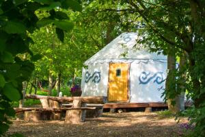 a small house with a yellow door in a forest at Elessar Yurt Village in Chichester