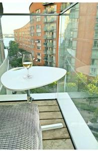 a glass of wine sitting on a table on a balcony at Private room in luxury canary wharf apartment in London