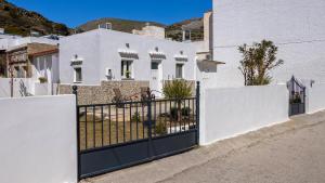 a white house with a gate in front of it at Salty Beach Cottage, 20m from Kini Beach in Ano Syros